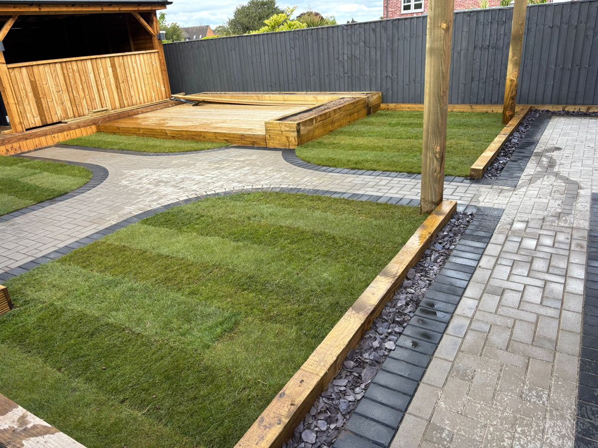 Landscaped garden with a shaped lawn, paved path and decking